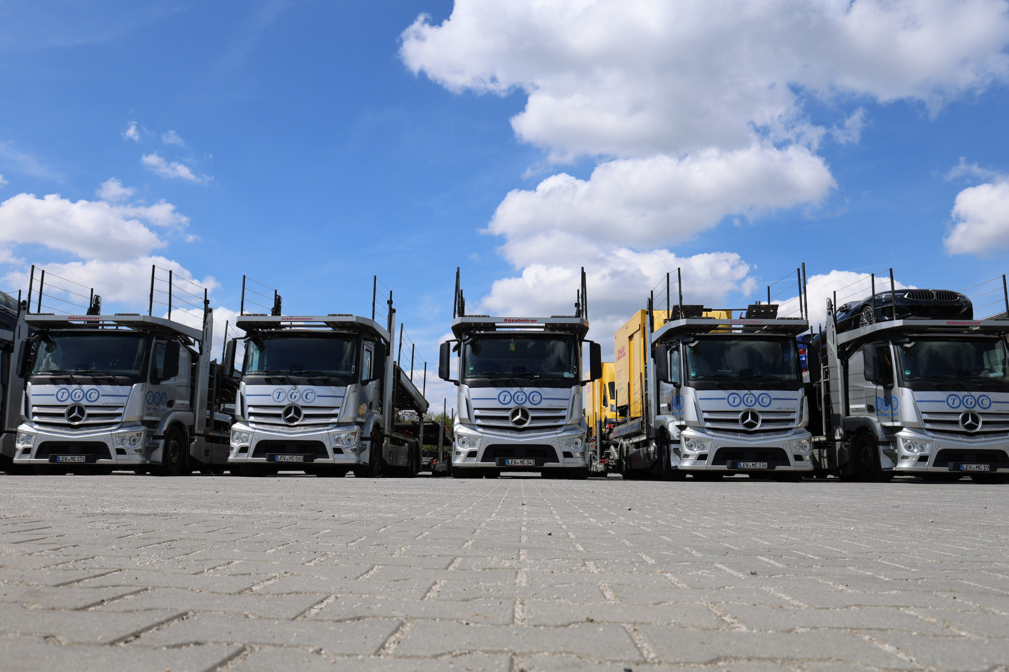 LKW-Flotte auf Parkplatz, Mercedes-Fahrzeuge unter blauem Himmel.